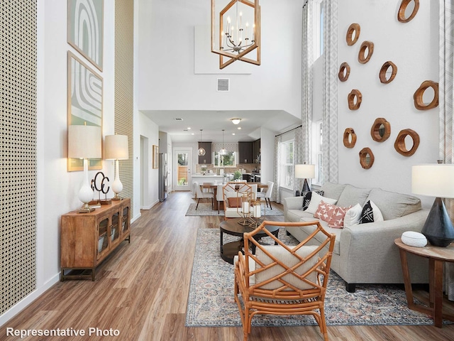 living room with hardwood / wood-style floors, a chandelier, and a high ceiling