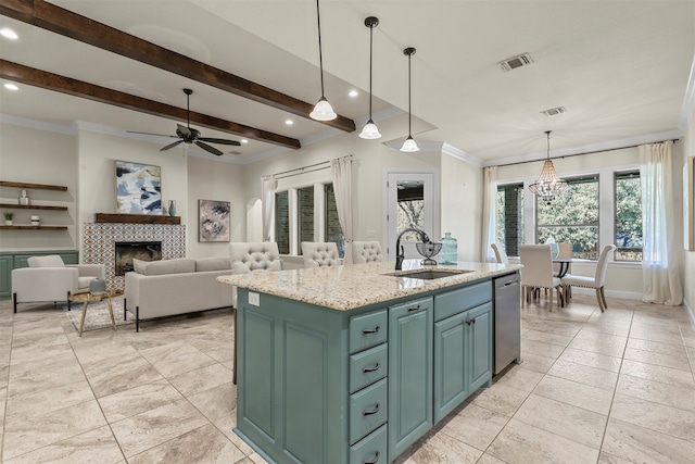 kitchen featuring a center island with sink, dishwasher, sink, a tile fireplace, and beam ceiling