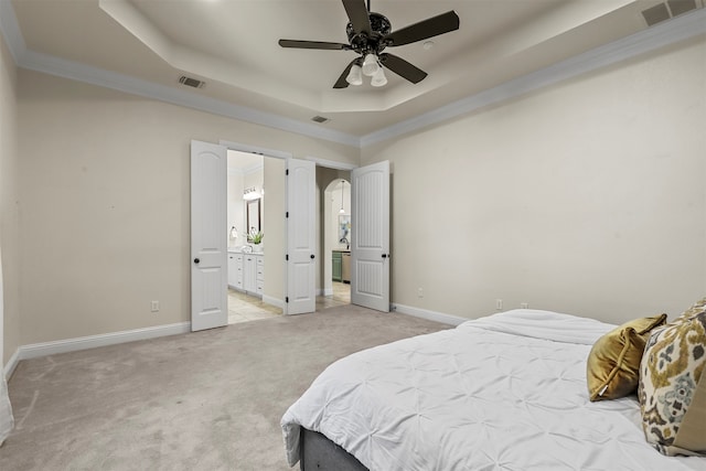 carpeted bedroom with ceiling fan, connected bathroom, a tray ceiling, and ornamental molding