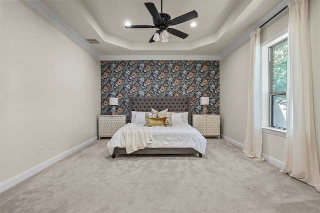 bedroom with ceiling fan, a raised ceiling, crown molding, and light colored carpet