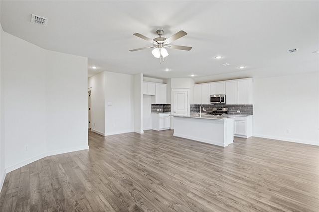 kitchen featuring visible vents, white cabinets, open floor plan, light countertops, and appliances with stainless steel finishes