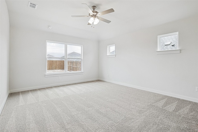 carpeted spare room featuring a ceiling fan, visible vents, and baseboards