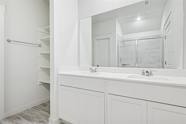 full bathroom with baseboards, double vanity, a sink, and a shower stall