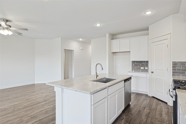 kitchen featuring stainless steel appliances, white cabinets, a sink, and a center island with sink