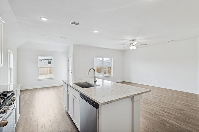 kitchen featuring visible vents, appliances with stainless steel finishes, a kitchen island with sink, a sink, and white cabinetry