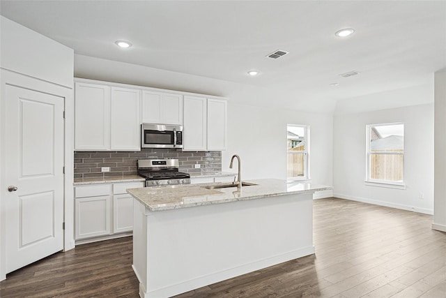 kitchen featuring stainless steel appliances, white cabinets, a sink, and an island with sink