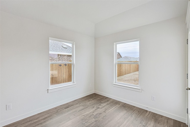 empty room featuring plenty of natural light, light wood-style flooring, and baseboards