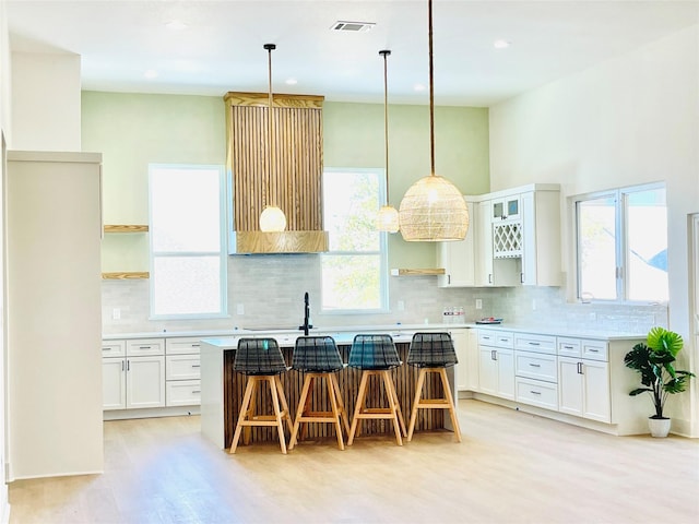 kitchen featuring a kitchen bar, tasteful backsplash, white cabinets, and a kitchen island