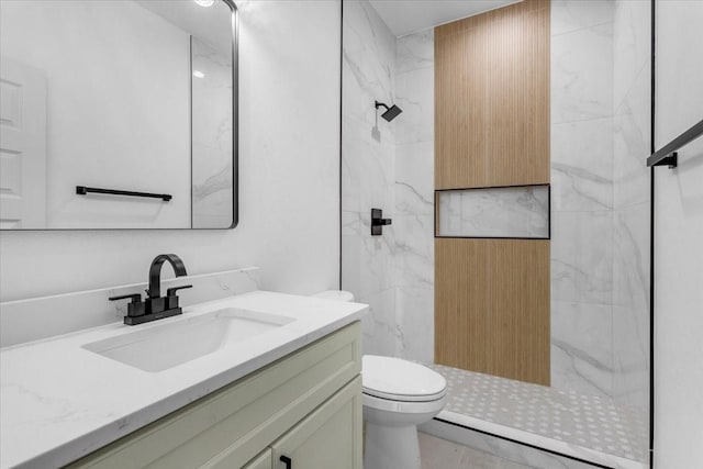 bathroom featuring tile patterned flooring, toilet, a tile shower, and vanity