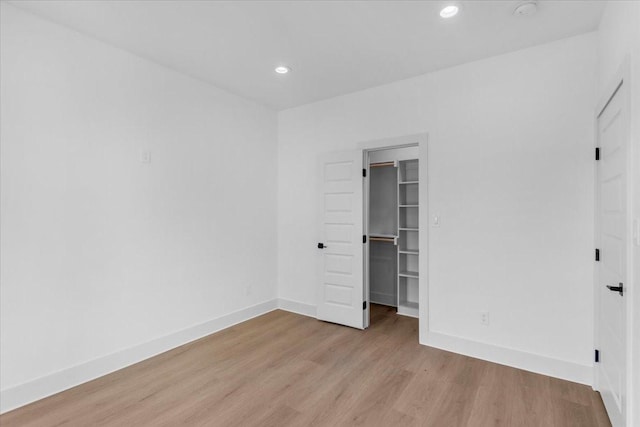 unfurnished bedroom featuring a closet, a walk in closet, and light hardwood / wood-style flooring