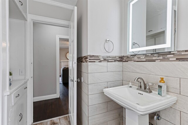 bathroom featuring toilet, sink, tile walls, and ornamental molding