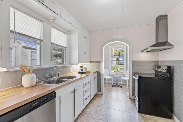 kitchen with wall chimney exhaust hood, white cabinetry, stainless steel appliances, and sink