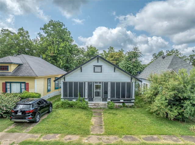 view of front of property featuring a front yard and a sunroom