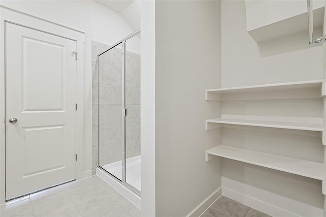 full bathroom with a shower stall and baseboards