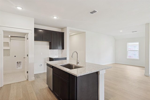 kitchen featuring light stone counters, a sink, visible vents, stainless steel dishwasher, and an island with sink