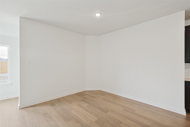 empty room featuring light wood finished floors, recessed lighting, and baseboards