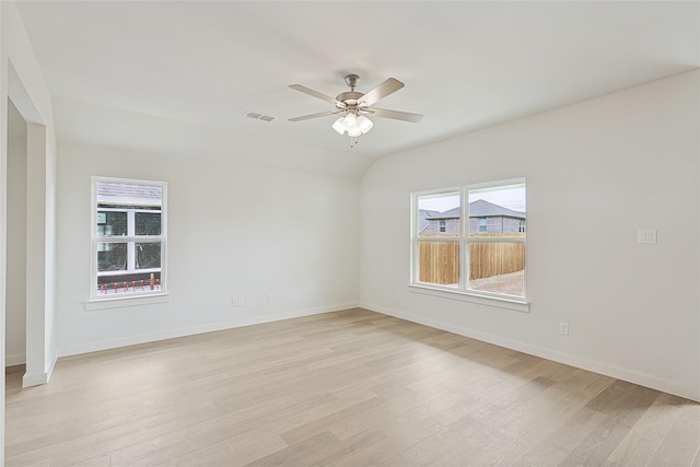 empty room featuring ceiling fan, lofted ceiling, visible vents, baseboards, and light wood-type flooring