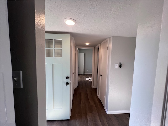 hallway with a textured ceiling and dark hardwood / wood-style floors