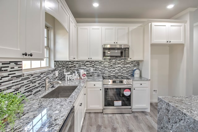 kitchen with light stone counters, crown molding, white cabinetry, appliances with stainless steel finishes, and sink