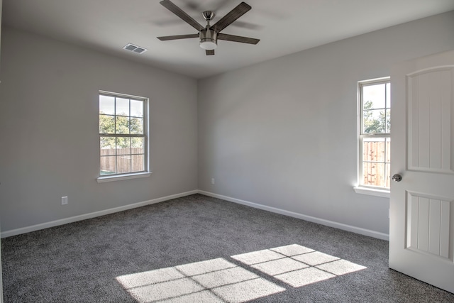 spare room featuring ceiling fan, plenty of natural light, and dark carpet