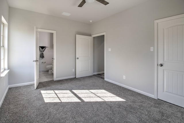 unfurnished bedroom with ensuite bath, ceiling fan, and dark colored carpet