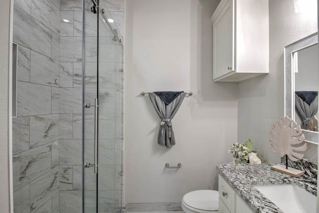 bathroom featuring toilet, vanity, and a shower with door