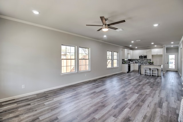 unfurnished living room featuring ornamental molding, light wood-type flooring, and ceiling fan