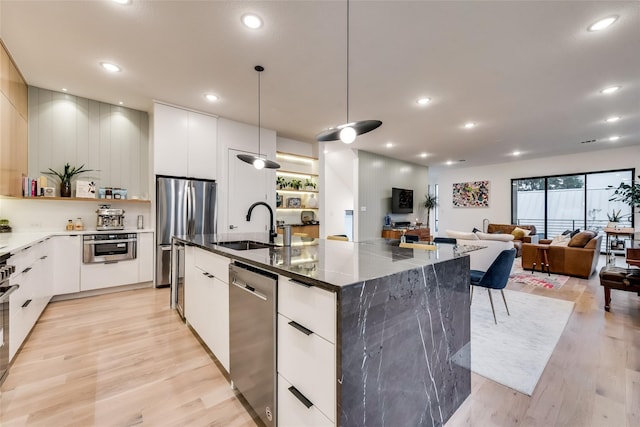 kitchen featuring appliances with stainless steel finishes, a spacious island, sink, pendant lighting, and white cabinetry