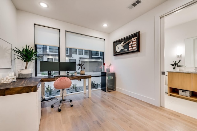 home office with wine cooler and light hardwood / wood-style floors