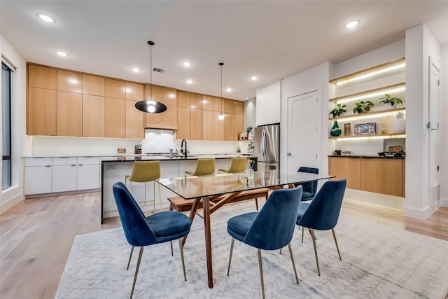 dining space featuring light wood-type flooring and sink