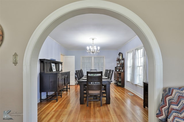 dining area with an inviting chandelier, light wood-type flooring, and ornamental molding