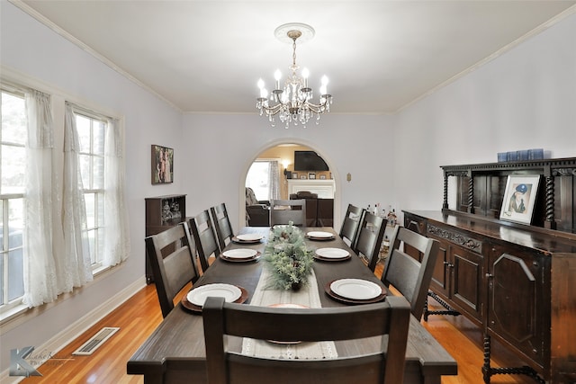 dining area with a chandelier, crown molding, and light hardwood / wood-style flooring