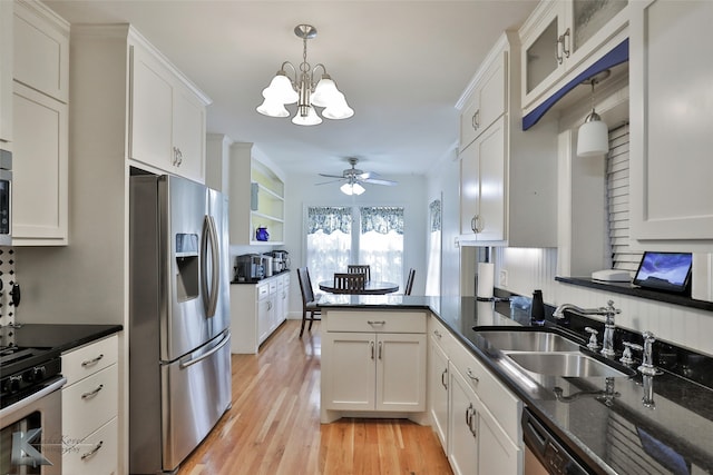 kitchen with white cabinets, kitchen peninsula, stainless steel appliances, and decorative light fixtures