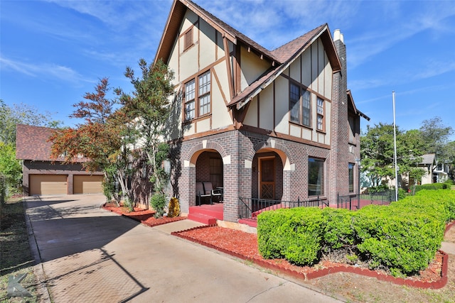 tudor-style house with an outbuilding, a garage, and covered porch