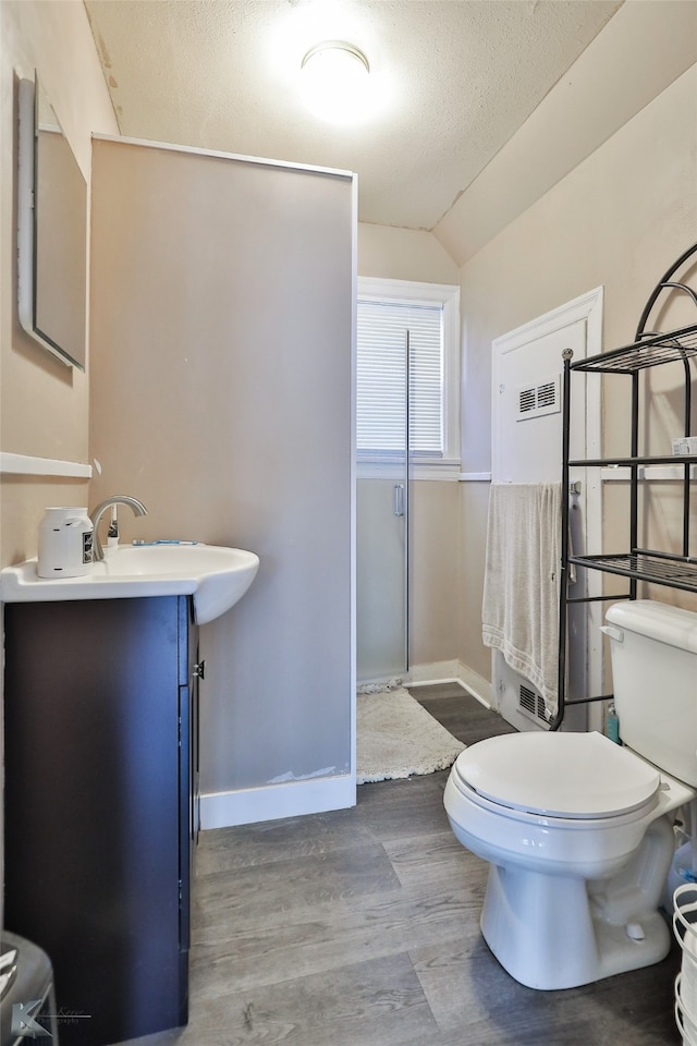 bathroom with lofted ceiling, toilet, a textured ceiling, hardwood / wood-style flooring, and vanity