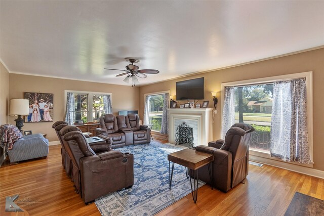 living room featuring ornamental molding, light wood-type flooring, and ceiling fan