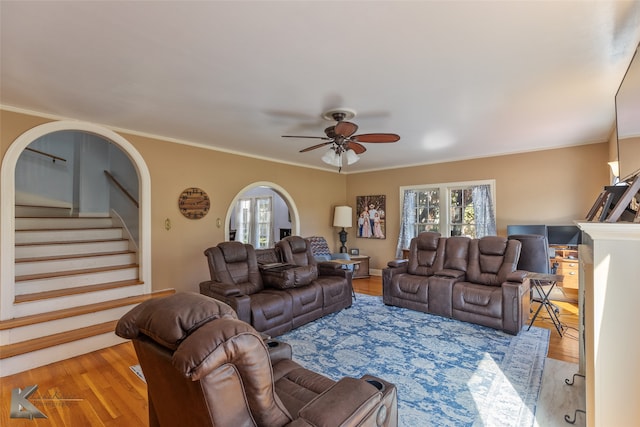 living room with light hardwood / wood-style floors, ceiling fan, and ornamental molding