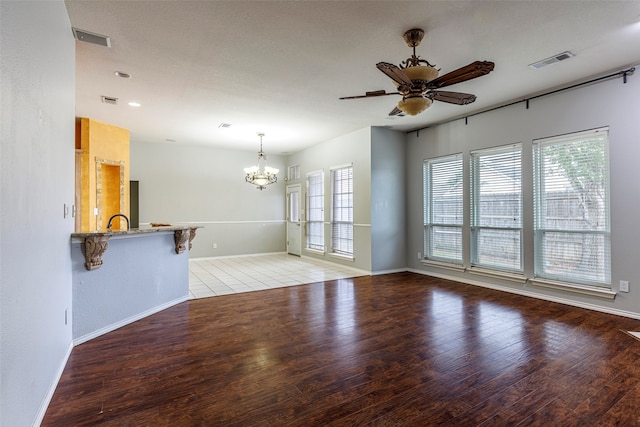 unfurnished room featuring ceiling fan with notable chandelier, a wealth of natural light, and light hardwood / wood-style flooring