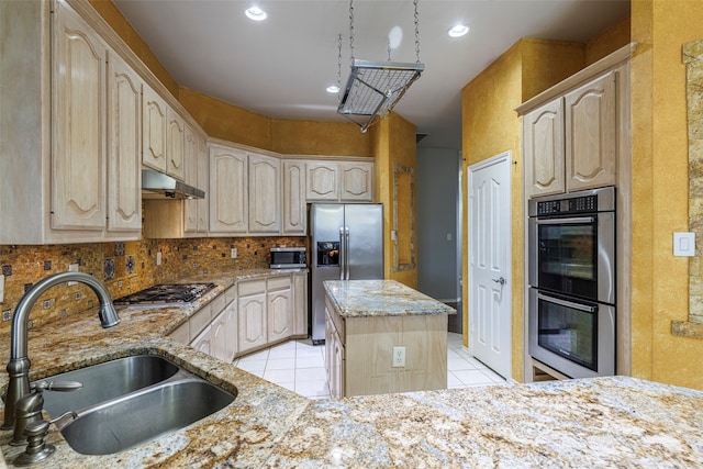 kitchen with stainless steel appliances, a center island, sink, light tile patterned floors, and light brown cabinetry