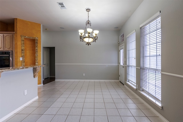 unfurnished dining area with a wealth of natural light, a notable chandelier, and light tile patterned floors