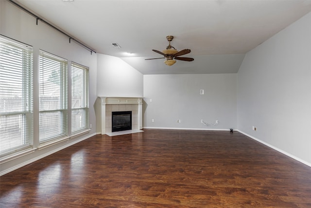 unfurnished living room featuring dark hardwood / wood-style flooring, vaulted ceiling, and a tile fireplace