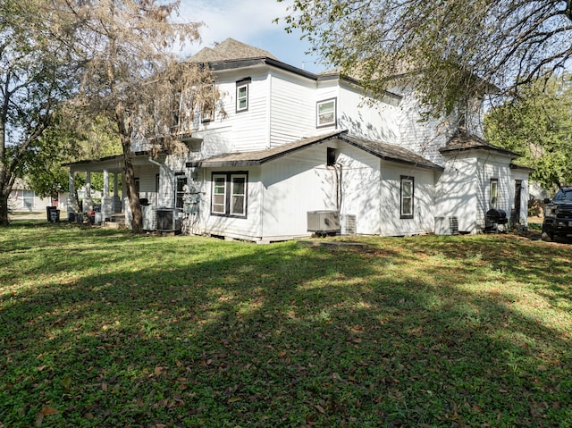 back of house with cooling unit and a yard