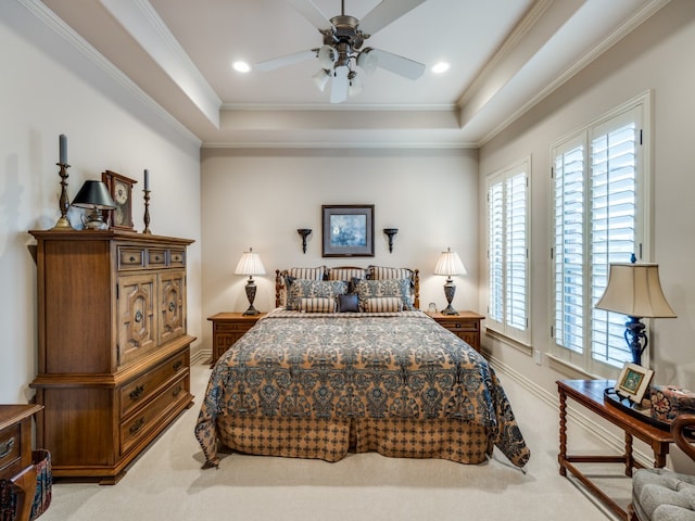 carpeted bedroom with ceiling fan, crown molding, and a tray ceiling