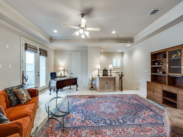 carpeted living room featuring ceiling fan, ornamental molding, and a raised ceiling