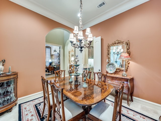 dining space with a chandelier, tile patterned floors, and ornamental molding