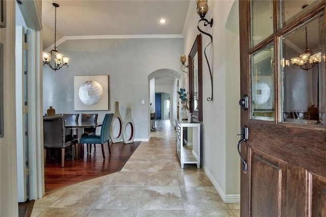 foyer entrance with light hardwood / wood-style floors, ornamental molding, and an inviting chandelier