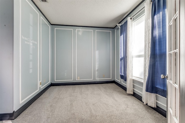 carpeted empty room featuring plenty of natural light and a textured ceiling