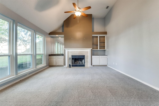 unfurnished living room with built in features, high vaulted ceiling, a fireplace, ceiling fan, and light carpet