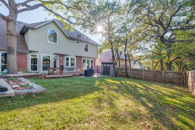 back of house featuring a wooden deck, a shed, and a lawn