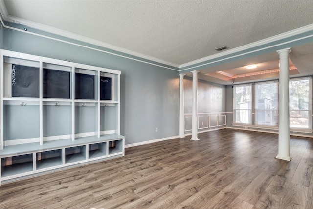 unfurnished living room featuring decorative columns, wood-type flooring, ornamental molding, a tray ceiling, and a textured ceiling